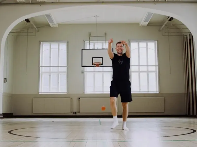 Aki celebrating after making a half-court basket in a gymnasium