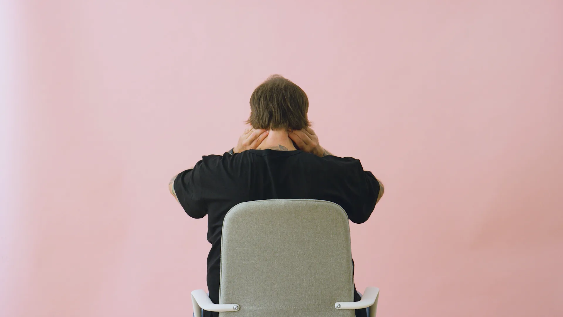 Person seated at a desk massaging the back of their neck